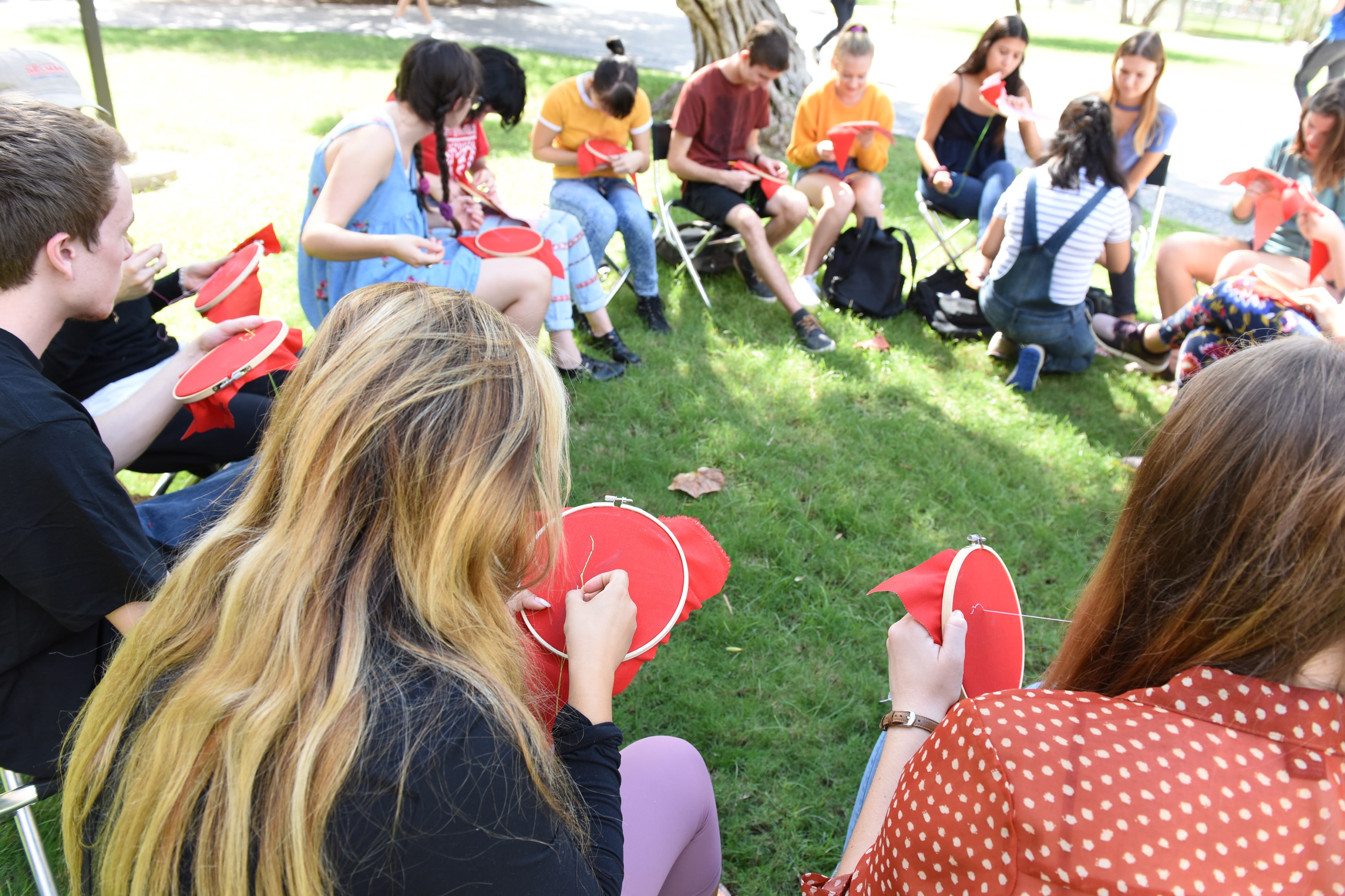 large group of students, sitting in a circle, learning hand-embroidery