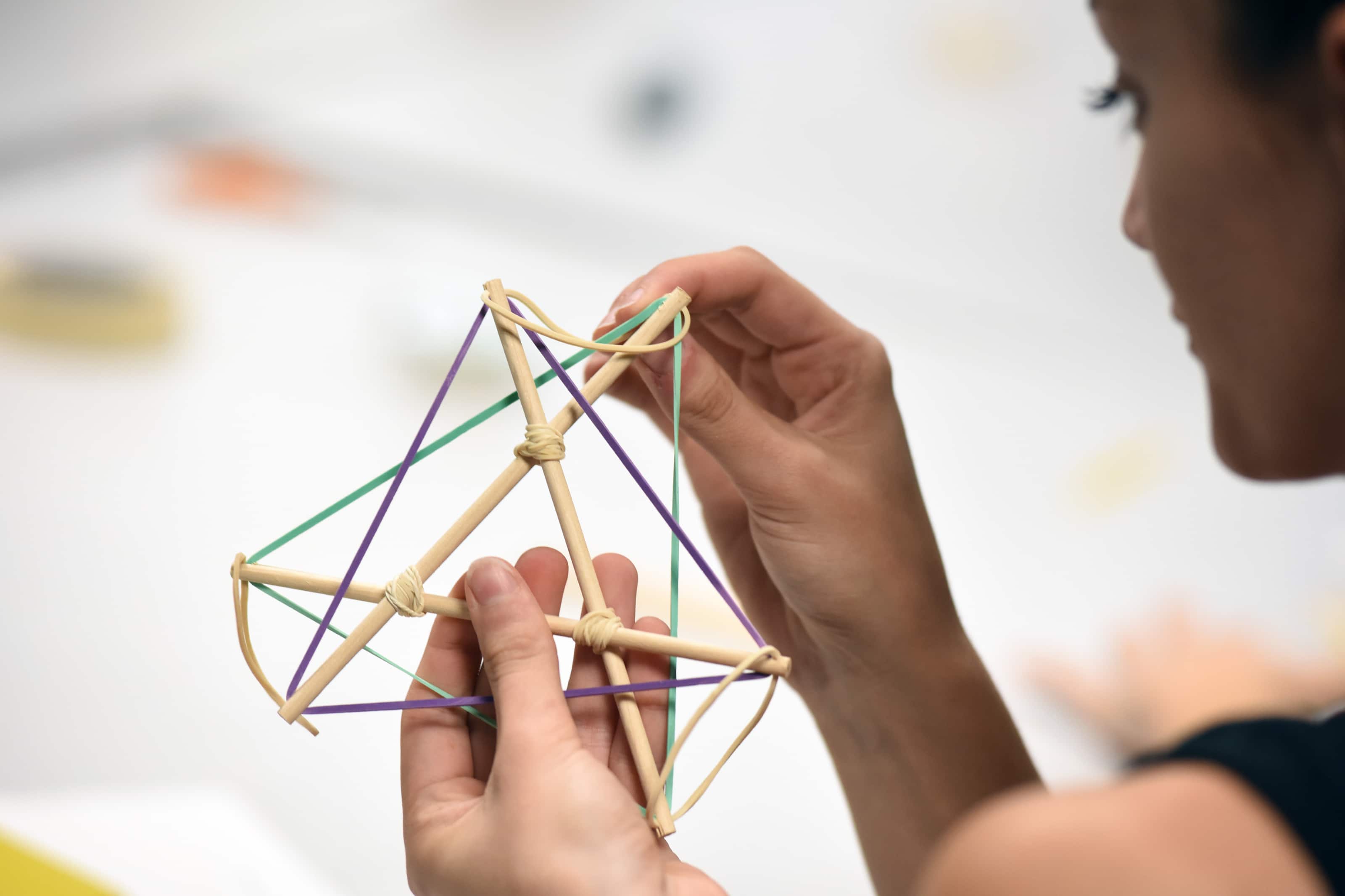 student holding a small 'tensegrity structure' that they created