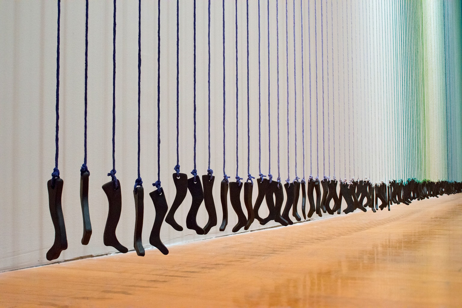 artwork: many small legs hanging from green, blue and white yarn